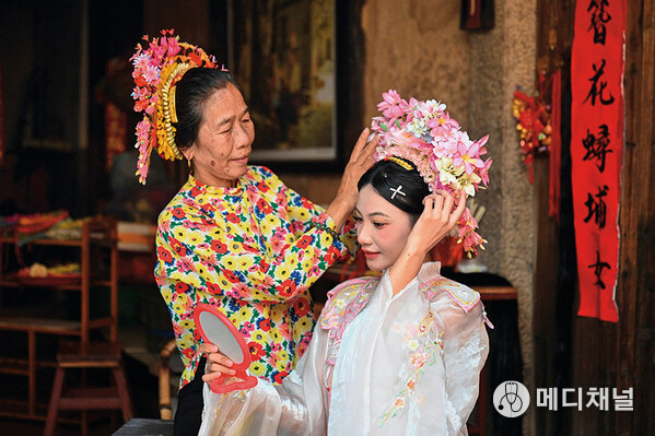 A tourist (right) is wearing flowery headwear at Xunpu Village of Quanzhou City, southeast China