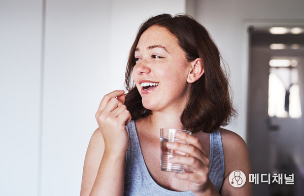 Young woman swallowing a small pill