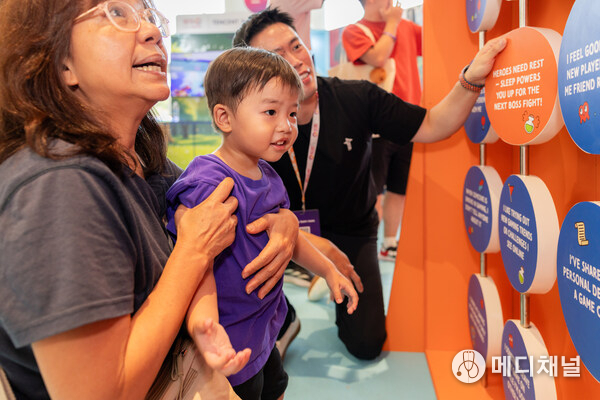 A family interacting with the “Stay in Control Flip Board” installation created by Tencent.