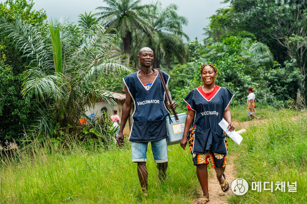 Vaccinators Helena Massah and Boakai Sesay walk into a remote village to check if any children still need polio vaccinations in Bong County, Liberia, on July 30, 2025. Carrying a vaccine cooler, they continue their door-to-door outreach. In rural areas like this, vaccinators often travel long distances - on foot or by motorbike - to ensure every child is reached with lifesaving protection against polio.